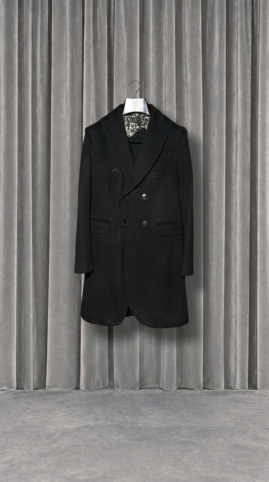Michael Melton Overcoat Men Black – product on hanger in front of the grey velvet curtain