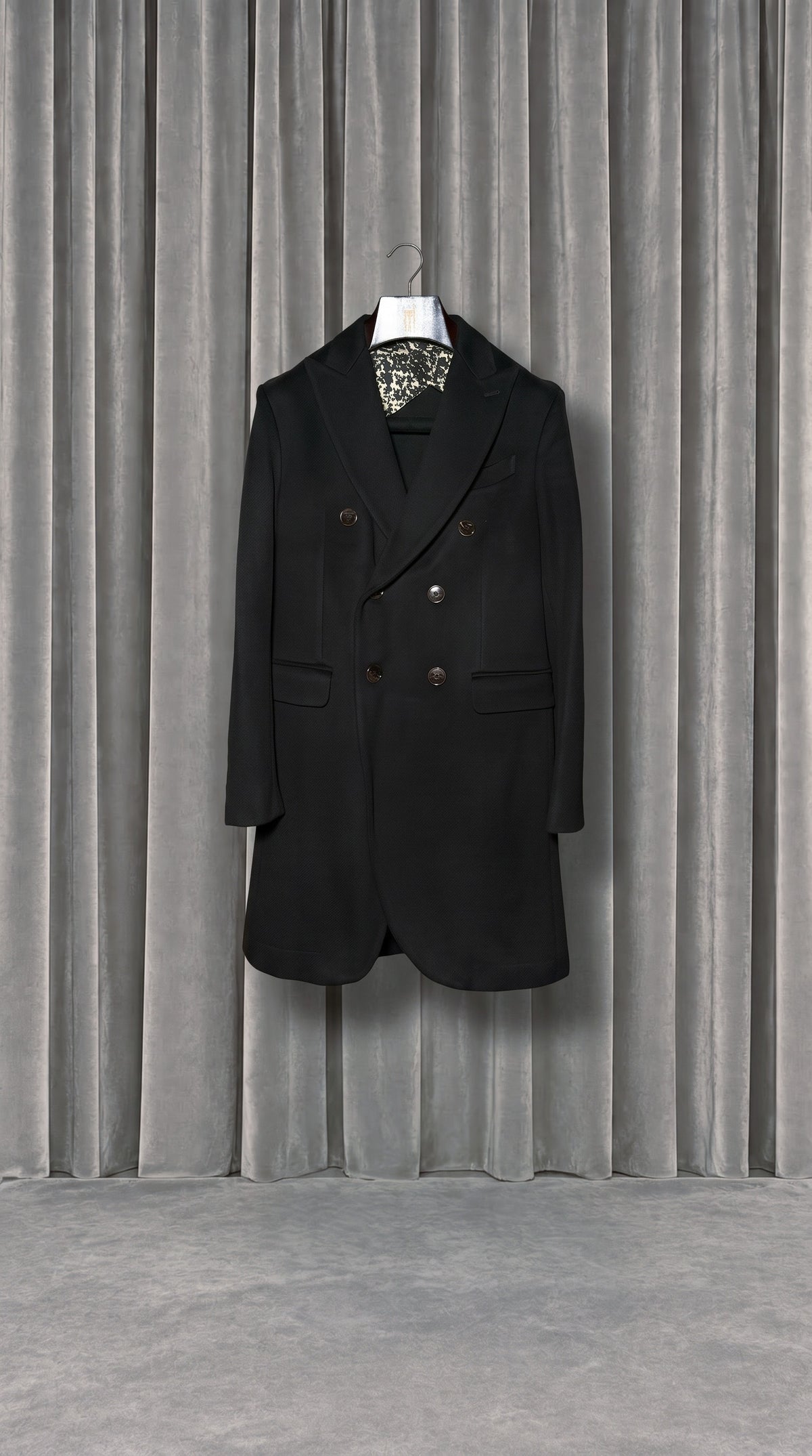Michael Melton Overcoat Men Black – product on hanger in front of the grey velvet curtain